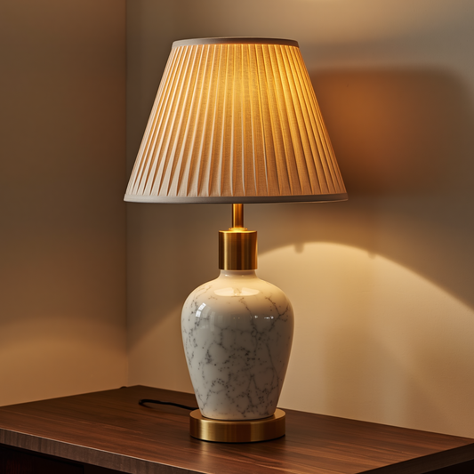 A classic white marble patterned ceramic table lamp with a pleated fabric shade placed on a dark wooden table.   