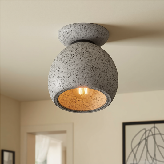 A modern grey speckled concrete semi flush mount ceiling light with a rounded shade and an exposed filament bulb mounted on a ceiling.